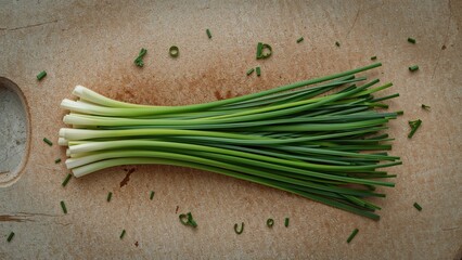 Fresh green onions on a cutting board with scattered chopped pieces. Fresh onion stalks, vegetables, and culinary ingredients. The concept of fresh produce and cooking ingredients.