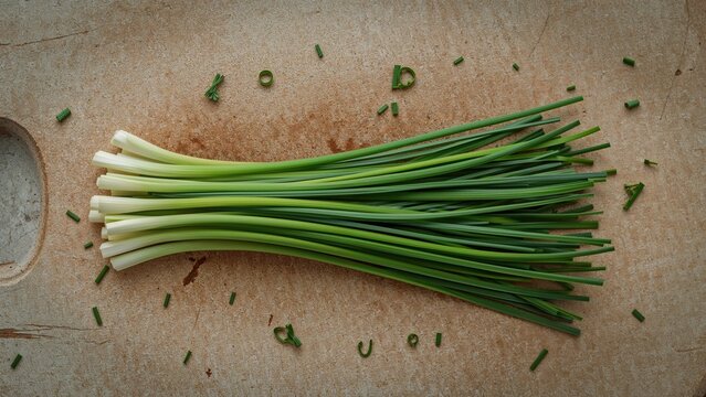 Fresh green onions on a cutting board with scattered chopped pieces. Fresh onion stalks, vegetables, and culinary ingredients. The concept of fresh produce and cooking ingredients.