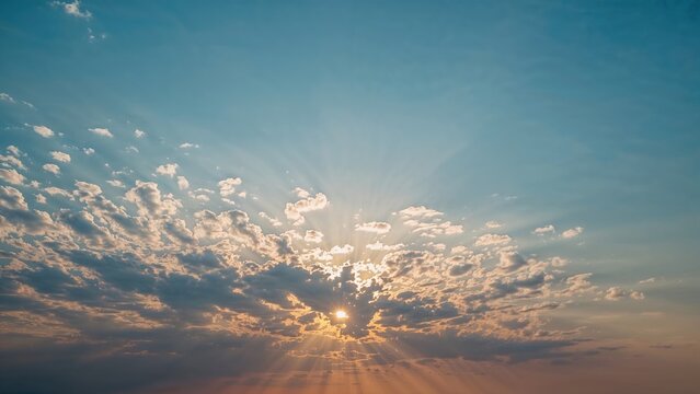 Sunset or sunrise sky with clouds and rays of light spreading outward.