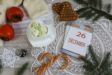 December 26 Calendar: The number 26 and the month's name in English on a decorative calendar surrounded by a lace napkin and Christmas sweets