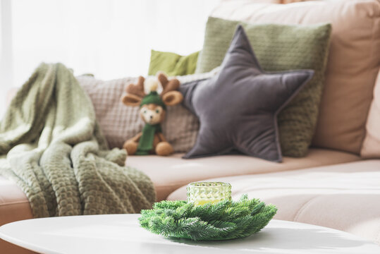 Cozy Living Room with Crocheted Reindeer Toy on Sofa and Christmas Holiday Candle Decor on Table - Powered by Adobe