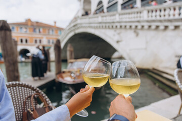 Couple toasting wine glasses in front of Rialto Bridge, Venice