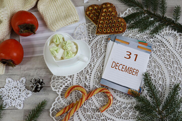 December 31st Calendar: The numbers 31 and the month's name in English on a decorative calendar surrounded by a lace napkin and Christmas sweets