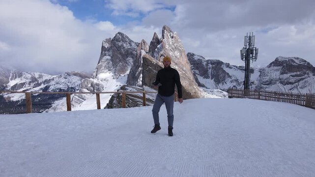 A drone captures a man walking high in the mountains using the follow-me feature, smoothly tracking him as he moves along the scenic alpine trail.