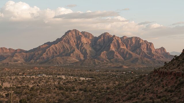 Mountain landscape with rugged peaks and sparse vegetation. Rocky terrain and a partly cloudy sky. - Powered by Adobe