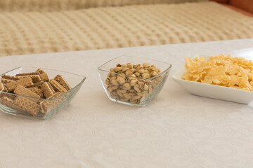 Three bowls with different types of snacks arranged in a row on a white table