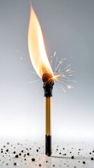 Flame igniting from a matchstick with sparks and a soft gray background in a minimalistic setting during daytime