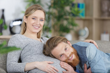 Obraz premium smiling man listening to his pregnant wifes belly