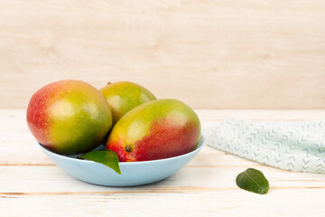 Fresh ripe mango with leaves on wooden table