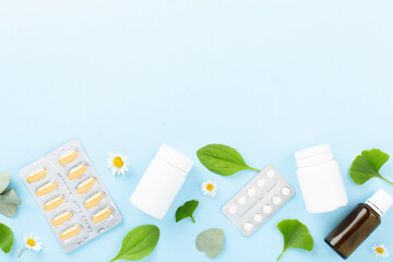 Herbs and flowers with medicines on color background, top view