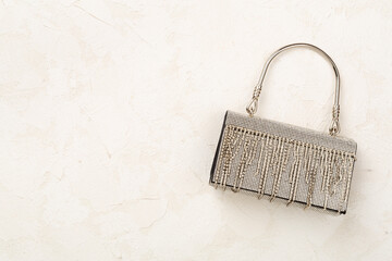 Handbag with beads on concrete background, top view