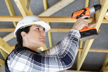female builder using cordless drill overhead
