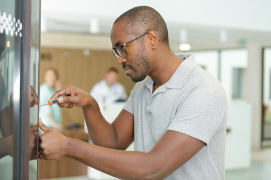 technician repair vending machine with screwdriver at hospital
