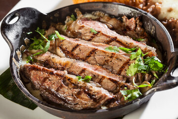 Slices of fresh cooked steak in an iron skillet with cilantro. 