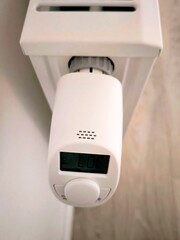 Digital thermostat on a white radiator with LOC and day of the week indicator. Top view.