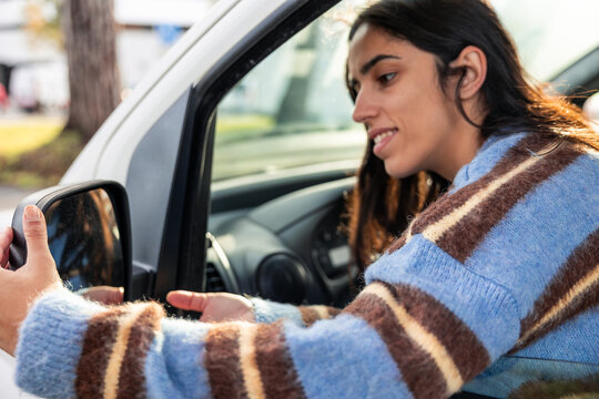 Young Latin woman adjusting car side mirror