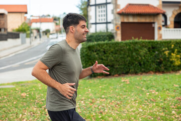 Latin man jogging outdoors in suburban park