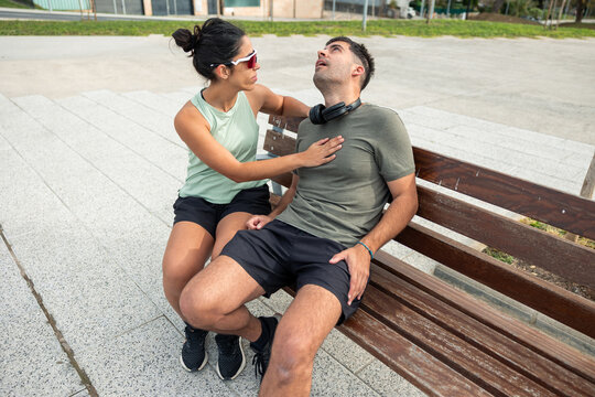 Worried woman helping man experiencing chest pain on bench