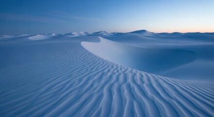 White sand dunes with beautiful wind ripples stretch across a vast, serene desert landscape under a clear blue twilight sky with a soft glow on the horizon