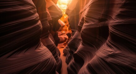 Wavy red sandstone rock formations inside a narrow slot canyon show geological layers carved by erosion, illuminated by warm sunlight