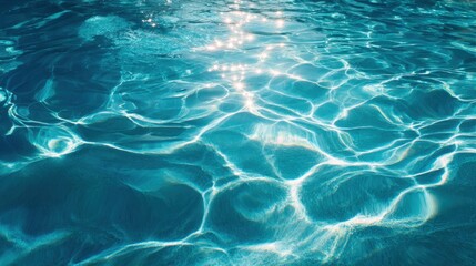 Obraz premium Bright sunlight creates shimmering patterns on the surface of clear blue water providing a sense of tranquility and beauty. The surface reflects the light beautifully enhancing the scene.