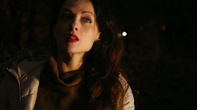 Elegant bright makeup smiling woman in elegant  clothes sitting on the bench in the dark evening outdoor autumn in studio light, empty copy space. Closeup face head portrait. Red lipstick, long hair
