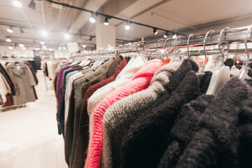 Colorful sweaters hanging on a rack in a modern retail store, showcasing various textures and styles, inviting customers to explore fashion choices and trends