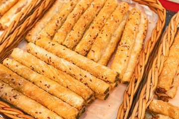 Freshly baked pastry rolls with sesame seeds arranged in woven baskets, showcasing golden-brown texture and flaky layers, perfect for culinary delights and snack options