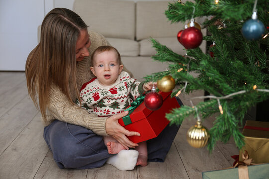 Mom and her adorable baby opening Christmas presents. Copy space, background.
