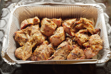 Close-up of grilled shashlik kebab pieces in a foil tray