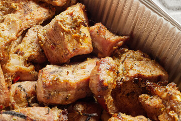 Close-up of grilled shashlik kebab pieces in a foil tray
