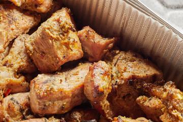 Close-up of grilled shashlik kebab pieces in a foil tray
