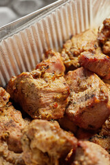 Close-up of grilled shashlik kebab pieces in a foil tray
