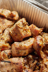 Close-up of grilled shashlik kebab pieces in a foil tray
