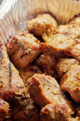 Close-up of grilled shashlik kebab pieces in a foil tray