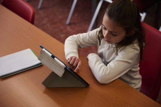 Young Student Studying With Tablet At Library Table In Classroom Setting For Learning