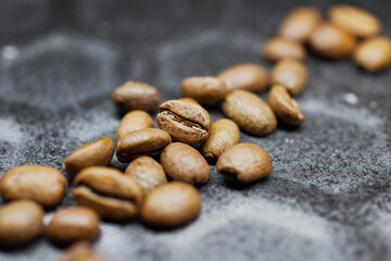 Close-up of a group of roasted coffee beans on a black baking tray background