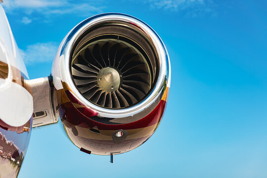 Close-up of a twin engine jets turbofan engine, and nacelle from below, front and top lit against clear blue sky.