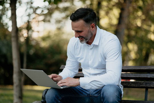 Smiling businessman working on laptop in park