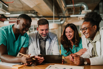 Diverse medical team collaborating laughing at tablet