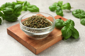 Fresh and dry basil leaves on light grey table, closeup