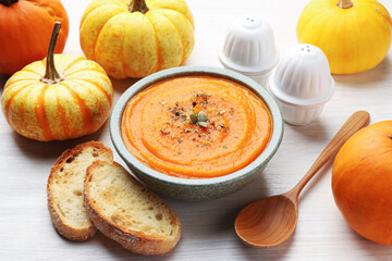Tasty pumpkin cream soup with seeds served on white wooden table, closeup