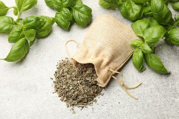 Fresh and dry basil leaves on light grey table, flat lay