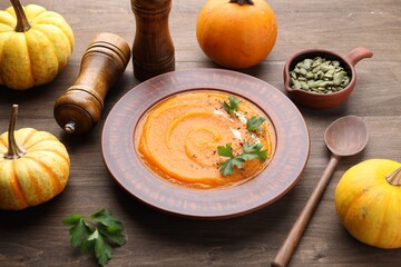 Tasty pumpkin cream soup in bowl served on wooden table, closeup