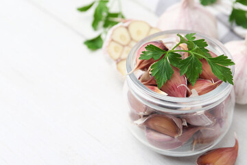 Garlic and parsley on white table, closeup. Space for text