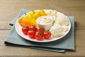 Different fresh vegetables and sauce on wooden table, closeup