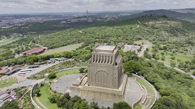 Drone flies backwards high over the right side of the Voortrekker Monument on a partly cloudy day in Pretoria, South Africa