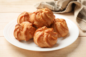 Delicious profiteroles and towel on white wooden table, closeup