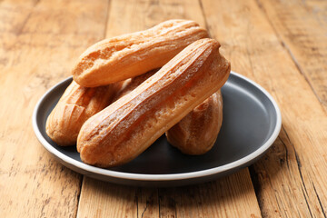 Delicious golden eclairs on wooden table, closeup