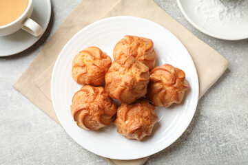 Delicious profiteroles, drink and powdered sugar on light grey table, flat lay